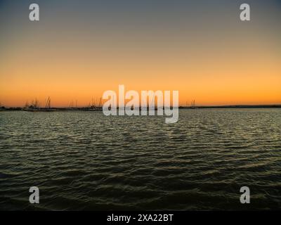 Ein Sonnenuntergang über dem Neusiedler See in Österreich, der Schilfgürtel und das Wasser in malerischen Farbtönen färbt Stockfoto