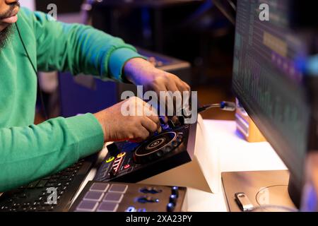 Toningenieur produziert neue Musik auf der Mischkonsole im Heimstudio, arbeitet mit Soundeffekten und Vorverstärkerregern. Erfahrener Produzent, der Songs erstellt und Lautstärkepegel anpasst. Nahaufnahme. Stockfoto