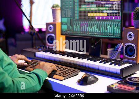 Sounddesigner arbeitet mit einer professionellen Bearbeitungssoftware auf dem pc, mischt und meistert seine alten Track-Aufnahmen im Heimstudio. Der Hersteller verwendet Stereoanlagen und Verstärker. Nahaufnahme. Stockfoto