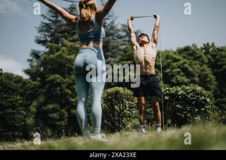 Ein junges Paar, das in einem sonnigen Park mit Widerstandsbändern trainiert Stockfoto