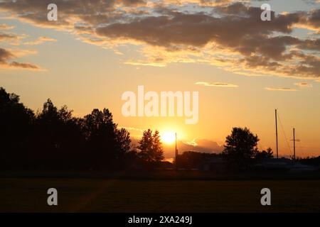 Die Sonne untergeht hinter zahlreichen hellen Wolken Stockfoto
