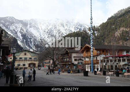 Einige Leute schlendern durch eine malerische Bergstadt mit alter Architektur, umgeben von Bergen Stockfoto