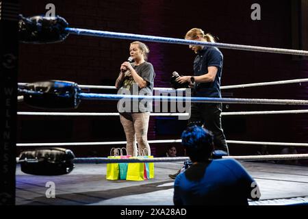Ein Profi-Wrestler und Freiwilliger steht im Ring, um für einige Waren zu werben und zu verschenken. Stockfoto