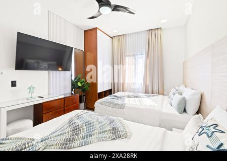 Ein weißes Bett in einem gemütlichen Schlafzimmer mit Fernseher und Sessel in der Nähe Stockfoto