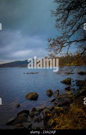 Eine dunkle Wolke wirft ein schimmerndes Spiegelbild auf dem Wasser unter einem düsteren Himmel in Ludvika, Schweden Stockfoto