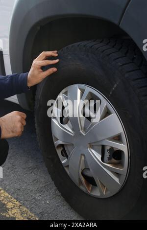 Mann, der sich auf das Auto lehnt und Reifen hält Stockfoto