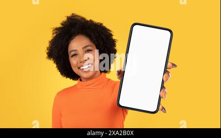 Lächelnde Afroamerikanerin, Die Ein Smartphone Mit Leerem Bildschirm Hält Stockfoto