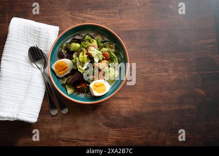 Ein Blick von oben auf einen Salat mit Eiern und Salat in einer Schüssel auf einem Holztisch Stockfoto