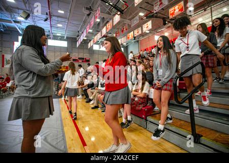 Multirassische uniformierte Schüler einer südkalifornischen katholischen High School nehmen nach einer schulweiten Messe im Gymnasium an der Kommunion Teil. Stockfoto