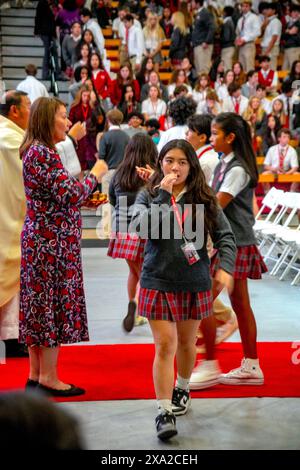 Multirassische uniformierte Schüler einer südkalifornischen katholischen High School nehmen nach einer schulweiten Messe im Gymnasium an der Kommunion Teil. Stockfoto