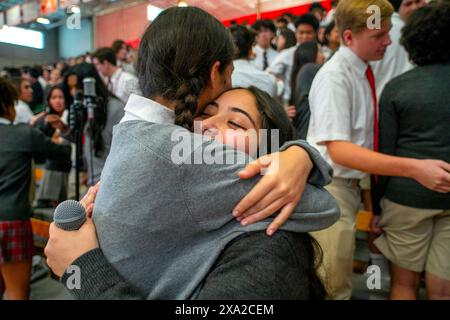 Multirassische uniformierte Schüler einer katholischen Highschool in Südkalifornien umarmen sich feierlich nach einer schulweiten Messe im Gymnasium. Stockfoto