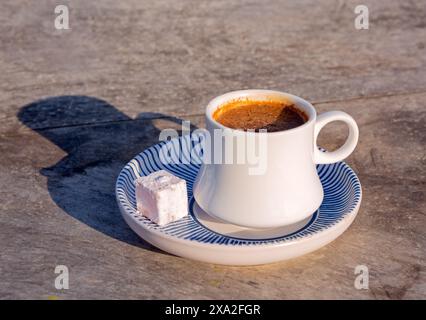 Am späten Nachmittag leuchtet eine Tasse türkischen Kaffee in einer weißen Tasse mit einer blau-weißen Untertasse Stockfoto
