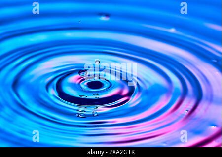 Ein Wassertropfen, der ins Wasser fällt und Wellen erzeugt Stockfoto