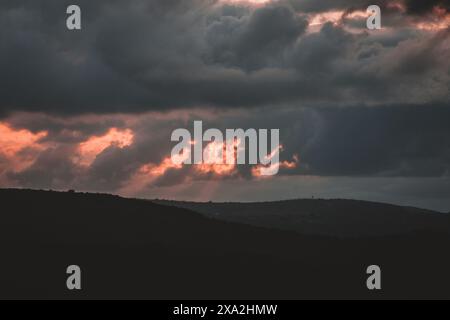 Dieses dramatische Foto fängt einen stürmischen Sonnenuntergang über den Hügeln Südafrikas ein und zeigt das Zusammenspiel von hellen und dunklen Wolken. Perfekt für Natur Stockfoto