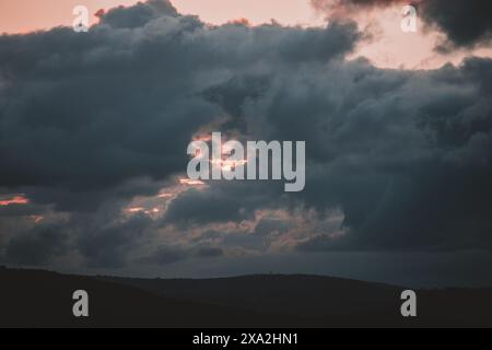 Ein dramatischer und stimmungsvoller Sonnenuntergang mit dunklen Wolken über die südafrikanischen Hügel. Dieses Foto ist perfekt für Natur- und Reiseinhalte und fängt die ganze Sache ein Stockfoto