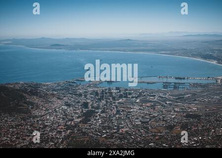 Erleben Sie den atemberaubenden Blick aus der Luft auf Kapstadt, Südafrika, mit seiner belebten Stadtlandschaft und dem weitläufigen Atlantik, eingerahmt von fernen Bergen Stockfoto