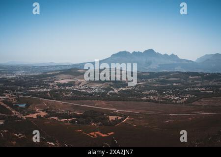 Atemberaubende Aussicht auf das Weinland Stellenbosch in Südafrika mit sanften Weinbergen, malerischen Ackerflächen und dramatischen Bergen unter einer Clea Stockfoto