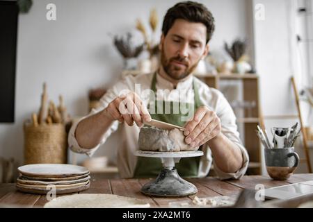 Lächelnder Mann, der in einem Töpferstudio mit Laptop arbeitet Stockfoto