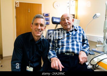 Thomas Poole, Augenarzt beim Frimley Health NHS Foundation Trust (links) mit dem Patienten Cecil Farley (rechts), während Frimley Health die erste kommerzielle Transplantation des Landes mit einer künstlichen Hornhaut im Frimley Park Hospital in Surrey durchführt. Bilddatum: Dienstag, 28. Mai 2024. Stockfoto