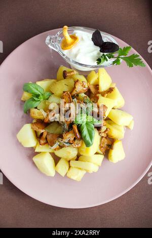 Ein Teller mit gekochten Kartoffeln mit Pfifferlingen und einer Sauce, garniert mit Basilikum und Petersilie Stockfoto