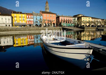 Wunderschöne Stadt Ascona an der Uferpromenade zum Lago Maggiore mit Reflexion und einem Boot an einem sonnigen Tag in Ascona, Tessin, Schweiz Stockfoto