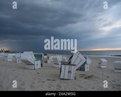 Verlassene Liegen am Strand unter dramatischem bewölktem Himmel, die Nordseeinsel baltrum mit grasbewachsener Düne, bunte Liegen am Strand Stockfoto