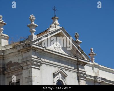 Detaillierter Blick auf ein historisches Gebäude mit architektonischen Details und einem Kreuz unter klarem Himmel, Lissabon, Portugal Stockfoto