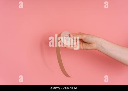 Klebeband für Gesicht in der Hand auf rosa Hintergrund Stockfoto