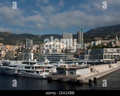 Seehafen mit Yachten und modernen Gebäuden im Hintergrund umgeben von Bergen und leicht bewölktem Himmel, monaco am französischen Mittelmeer Stockfoto