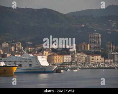 Hafenstadt mit mehreren Schiffen und Booten, vor grünen Bergen und bewölktem Himmel, Korsika, ajaccio, Frankreich Stockfoto