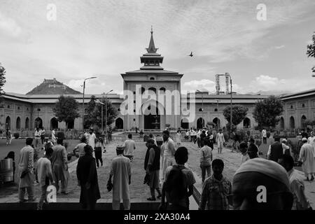 Schwarz-weiß-Bild von Menschen im Innenhof einer großen Moschee mit historischer Architektur, Srinagar, Jammu und Kaschmir, Indien Stockfoto