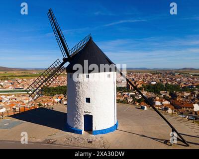 Eine traditionelle Windmühle mit weißen und blauen Farben vor einem Dorf und einem weiten Himmel, aus der Luft, Consuegra, Toledo, Castilla-La Mancha, Spanien Stockfoto