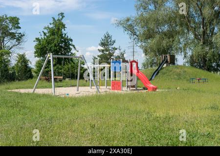 Verlassener Spielplatz mit Rutsche, Klettergerüst und Schaukel am Mittag Stockfoto