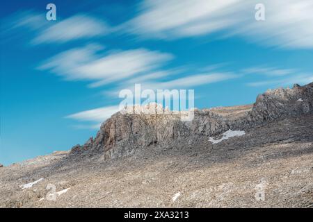 Felsiger Hügel mit Wolken im Hintergrund an einem sonnigen Tag Stockfoto