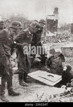 Nazi-Soldaten beobachten russische Frauen, die nach einem Bombenangriff auf Stalingrad im Zweiten Weltkrieg 1942 aus einem Keller auftauchten. Aus dem Krieg in Bildern, 4. Jahr. Stockfoto