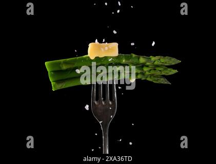 Grüner Spargel mit schmelzender Butter und Salz auf einer Gabel Stockfoto