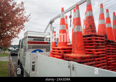 Arbeitsfahrzeug beladen mit temporären Schildern und schmutzigen orangefarbenen Kegeln am Straßenrand. Bauarbeiten in Auckland. Stockfoto