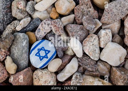 Israelische Flagge gemalt. Handgemalter Stein mit Magen David und anderen Felsen am Kieselstrand Stockfoto