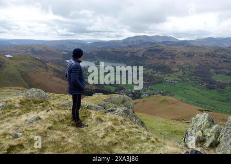 Man (Wanderer) auf dem Wainwright „Stone Arthur“ über Grasmere Village & Grasmere Lake im Lake District National Park, Cumbria, England, Großbritannien. Stockfoto