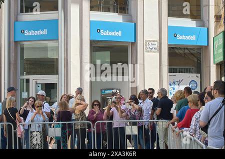 Sitges, Barcelona, Spanien-03. Juni 2024: Crowd beobachtet an einem sonnigen Tag eine Blumenausstellung auf der Straße der Banco Sabadell Niederlassung in Sitges. Stockfoto