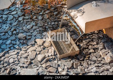 Moderner Wasserfall im Garten ohne Teich in einem Hinterhof mit Schiefersteinen Stockfoto