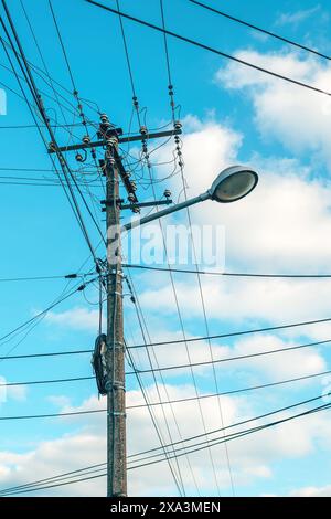 Straßenleuchte mit Stromanschluss und unordentlichen Stromkabeln am Himmel, geringer Blickwinkel Stockfoto