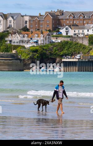 Ein Mann und sein Hund spazieren am Towan Beach in Newquay in Cornwall, Großbritannien. Stockfoto