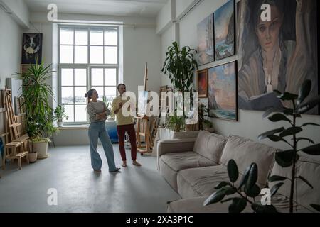 Glückliche glückliche, dass ein paar verliebte Künstler über Kunst sprechen, die sich Gemälde anschauen, die in den Wohnungen hängen Stockfoto