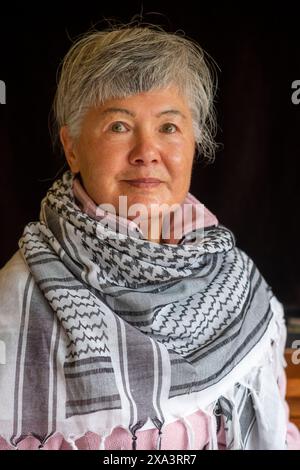 Eine ältere eurasische Chinesin/Italienerin, die einen Keffiyeh trägt, um ihre Unterstützung für Palästina zu demonstrieren Stockfoto