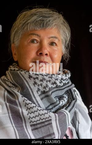 Eine ältere eurasische Chinesin/Italienerin, die einen Keffiyeh trägt, um ihre Unterstützung für Palästina zu demonstrieren Stockfoto