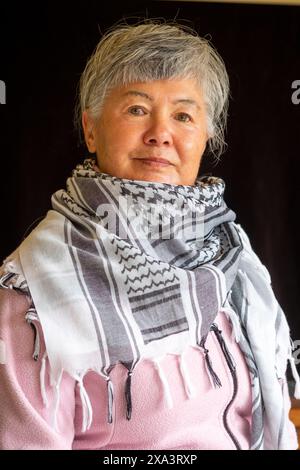 Eine ältere eurasische Chinesin/Italienerin, die einen Keffiyeh trägt, um ihre Unterstützung für Palästina zu demonstrieren Stockfoto