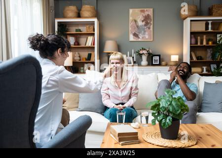 Zwei Leute, junge, vielfältige Paare, die versuchen, Probleme in ihrer Beziehung zu lösen. Multirassische Ehepartner lächeln, während sie sich vor einem Therapeuten in der Th unterhalten Stockfoto