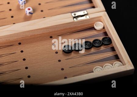 Brett zum Spielen von Backgammon mit Stücken und Würfeln auf schwarzem Hintergrund. Brettspiel, Zeitvertreib, Spaß. Stockfoto