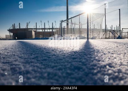 Gefrorener Fußballplatz mit Schnee und Stadion im Hintergrund Stockfoto